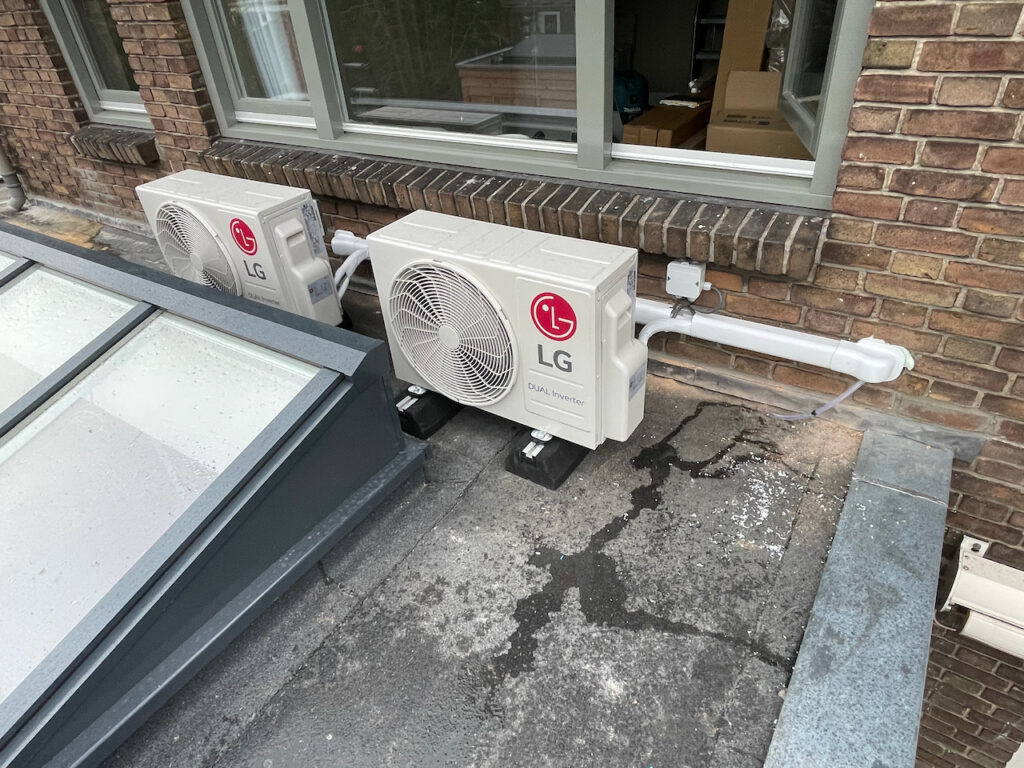 Twee LG buitenunits van een airco- of warmtepompsysteem geplaatst op een plat dak en gereed voor periodiek onderhoud